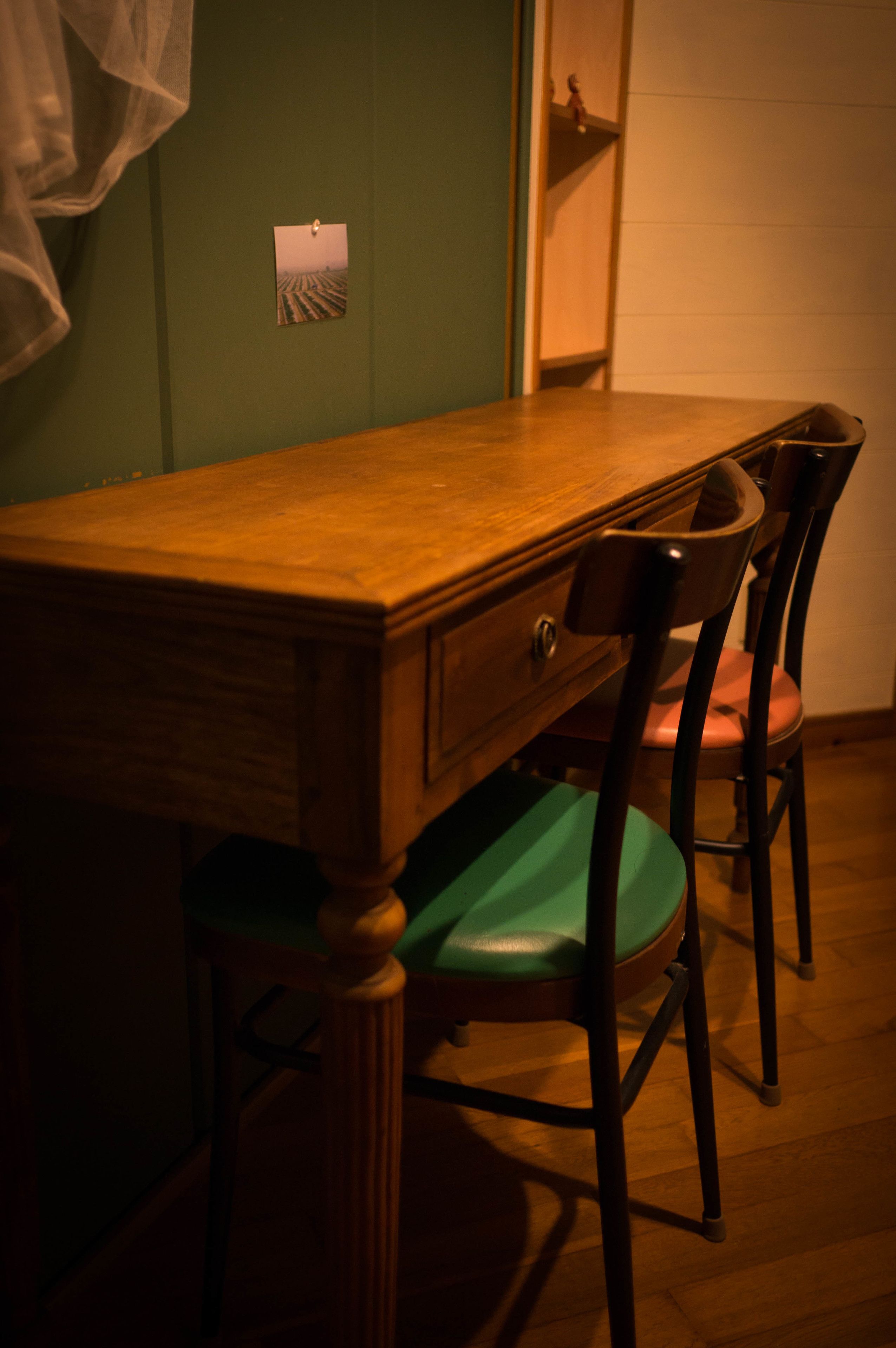 Une table à manger avec des chaises, un plancher en bois et un mur vert.