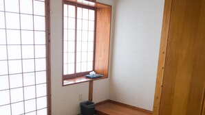 A tatami mat room with a round table, sliding doors, and a window with a view. - Amakara Okinawa (Nago)