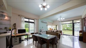 A spacious living area with a dining table, chairs, a TV, and a kitchen area with a refrigerator and sink. - Slow Fly B&B (Xincheng)