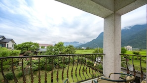 A balcony with a wicker chair and a view of a green landscape with mountains in the distance. - Slow Fly B&B (Xincheng)