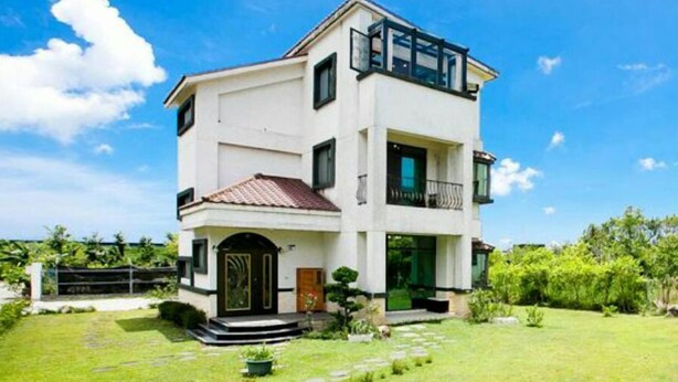 A two-story house with a balcony on the upper floor, a front door, and a small front yard. - Slow Fly B&B (Xincheng)