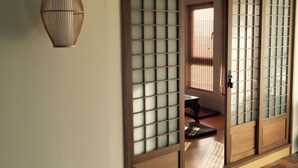A traditional Japanese room with sliding doors, a tatami mat, and a hanging lamp. - Celine's B&B (Fenglin)