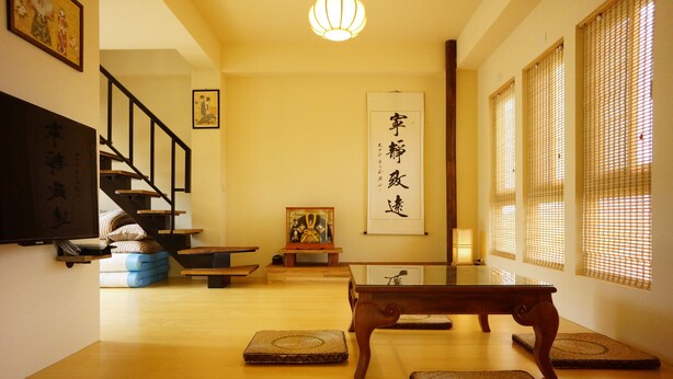 A traditional Japanese room with tatami mats, a low wooden table, a sofa, and a staircase. - Celine's B&B (Fenglin)