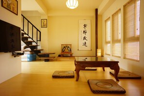 A traditional Japanese room with tatami mats, a low wooden table, a sofa, and a staircase.