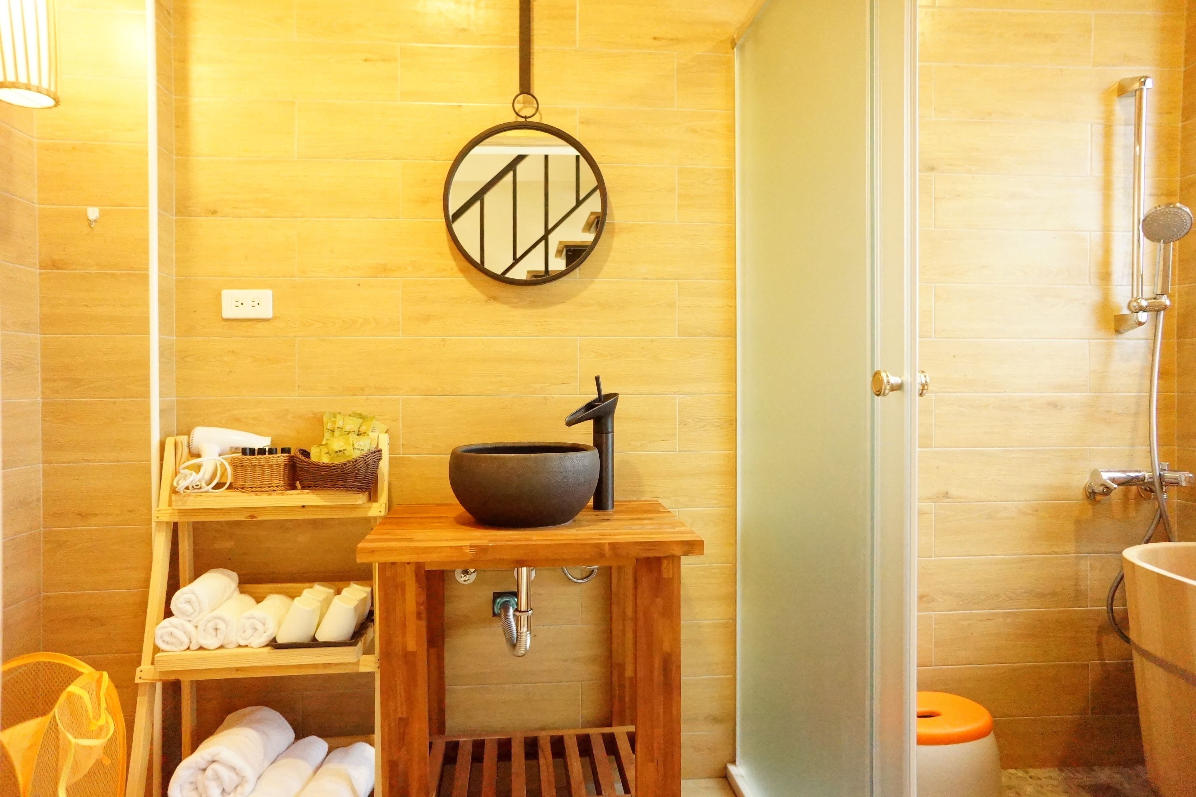 Ein Badezimmer mit einem Holzkosmetikschrank, einem großen Spiegel, einem Waschbecken und einer Duschkabine.