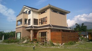 A two-story house with a balcony on the upper floor, a front porch, and a wooden fence. - Celine's B&B (Fenglin)