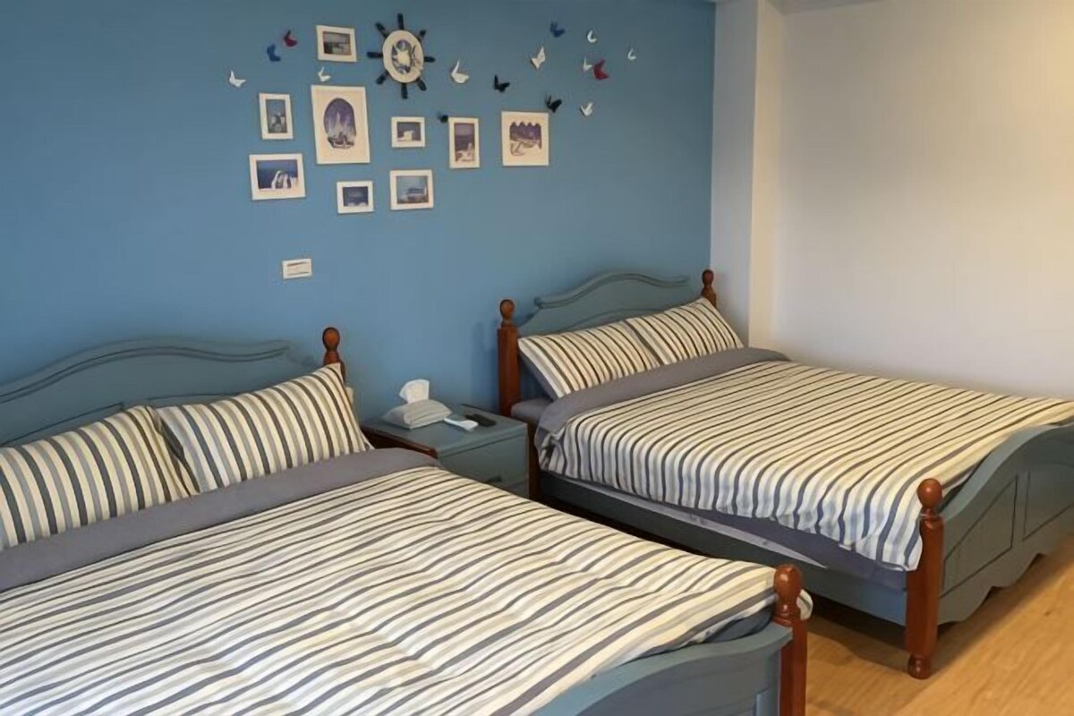 Dos camas individuales con ropa de cama a rayas, una mesita de noche y una pared decorada con imágenes y pequeñas figuras.