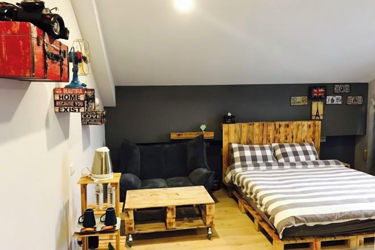 Una habitación compacta con cama, sofá, una mesita y cafetera.