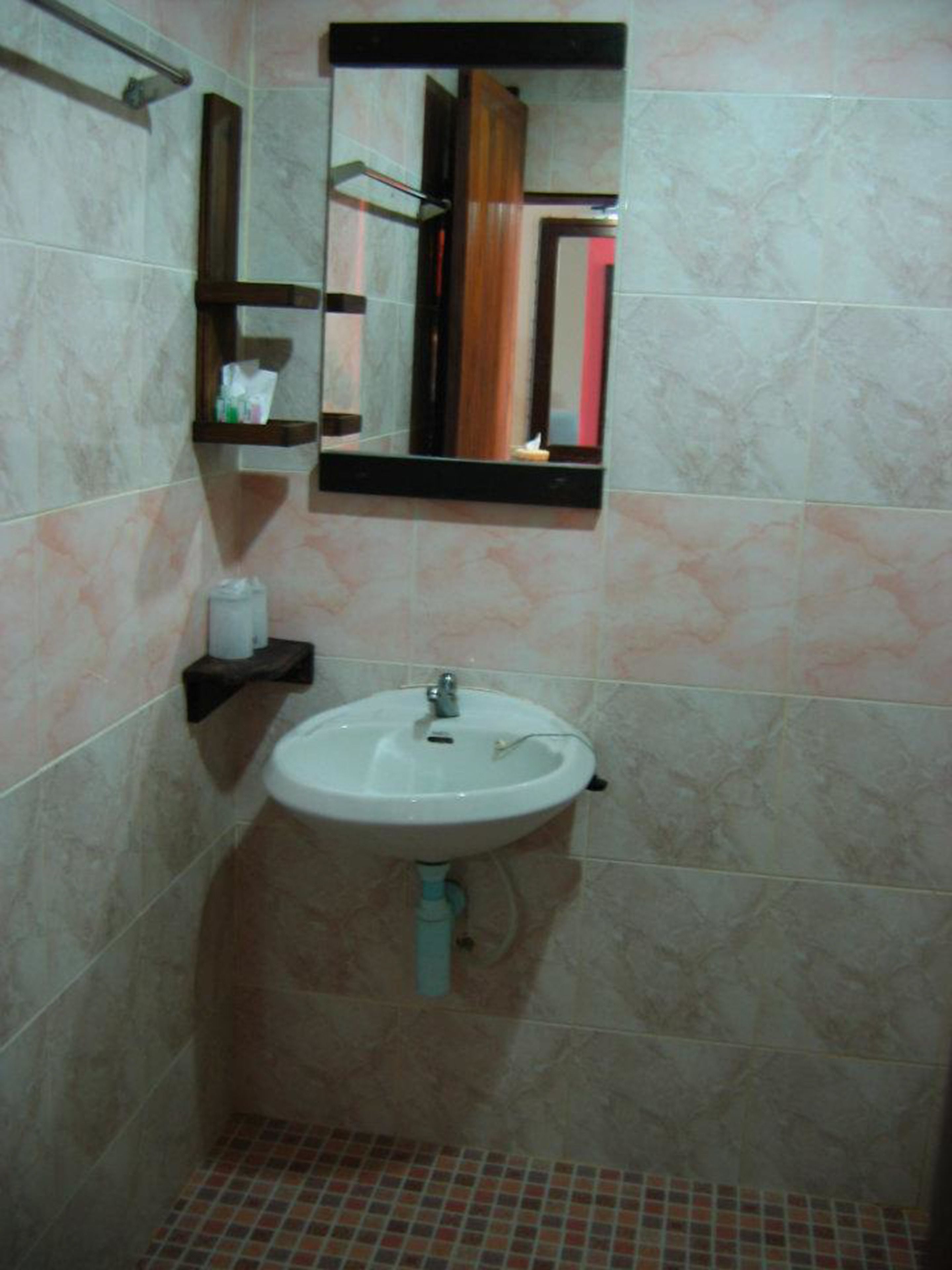 A bathroom with a white sink, a mirror above it, and a towel rack.