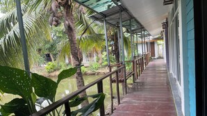 A wooden deck with a metal railing, surrounded by lush greenery and a body of water. - Ruen Kaew Boutique Resort (Sung Men)