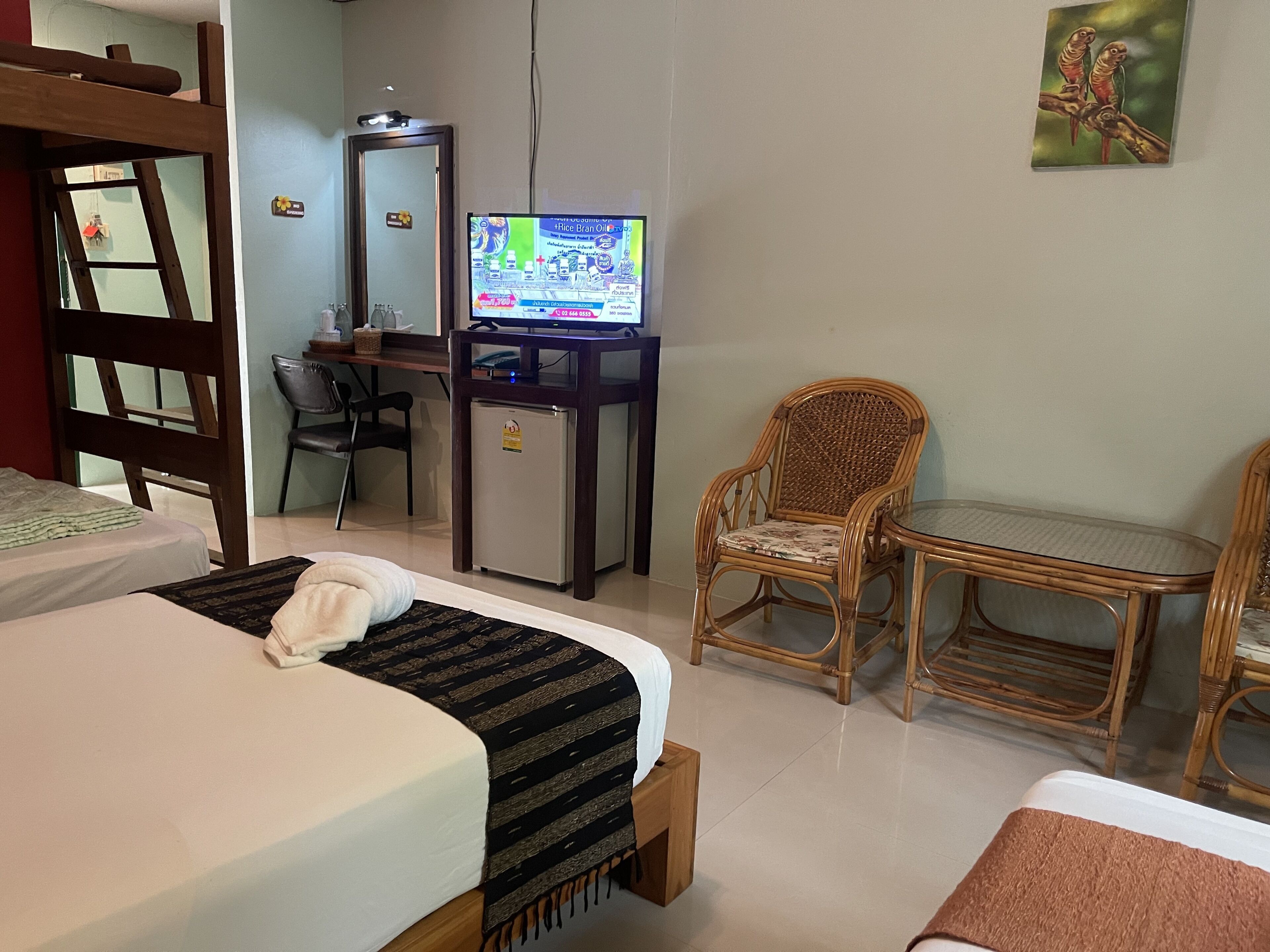 Une chambre d’hôtel équipée d’un lit, d’un bureau avec un ordinateur, d’une chaise, d’un petit réfrigérateur et d’une télévision.