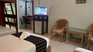 Habitación de hotel con cama, escritorio con computadora, silla, refrigerador pequeño y televisor.