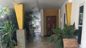 A hallway with a wooden bench, large potted plants, and patterned floor tiles. - Ruen Kaew Boutique Resort (Sung Men)