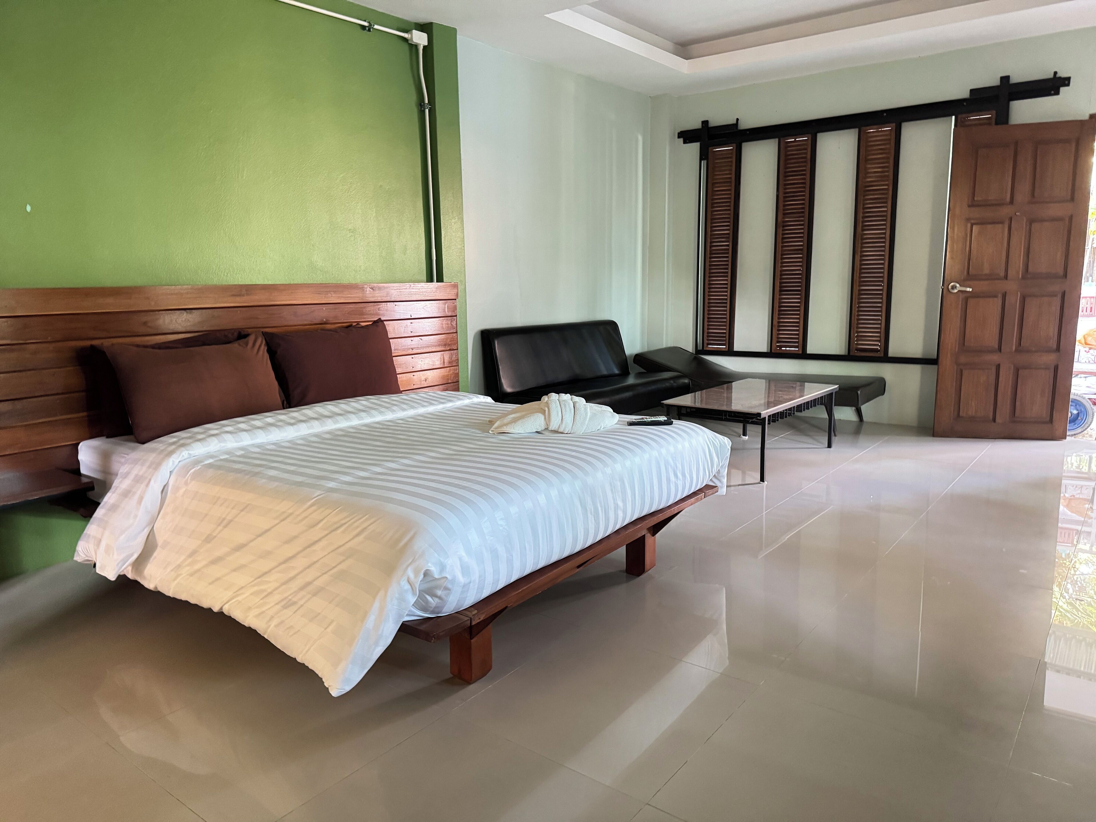 Habitación de hotel con una cama grande, un sofá, una mesita y una puerta corredera.