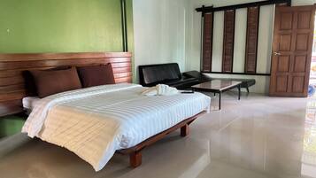 Habitación de hotel con una cama grande, un sofá, una mesita y una puerta corredera.