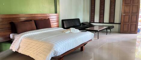 Habitación de hotel con una cama grande, un sofá, una mesita y una puerta corredera.