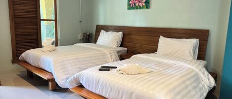 Una camera d'albergo con due letti, una panca, un quadro e una finestra.