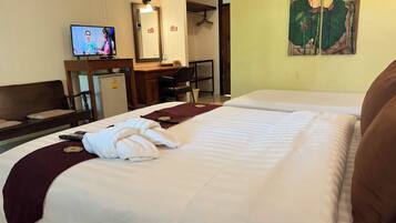 A hotel room with two beds, a desk, a television, a mirror, and a wall painting.