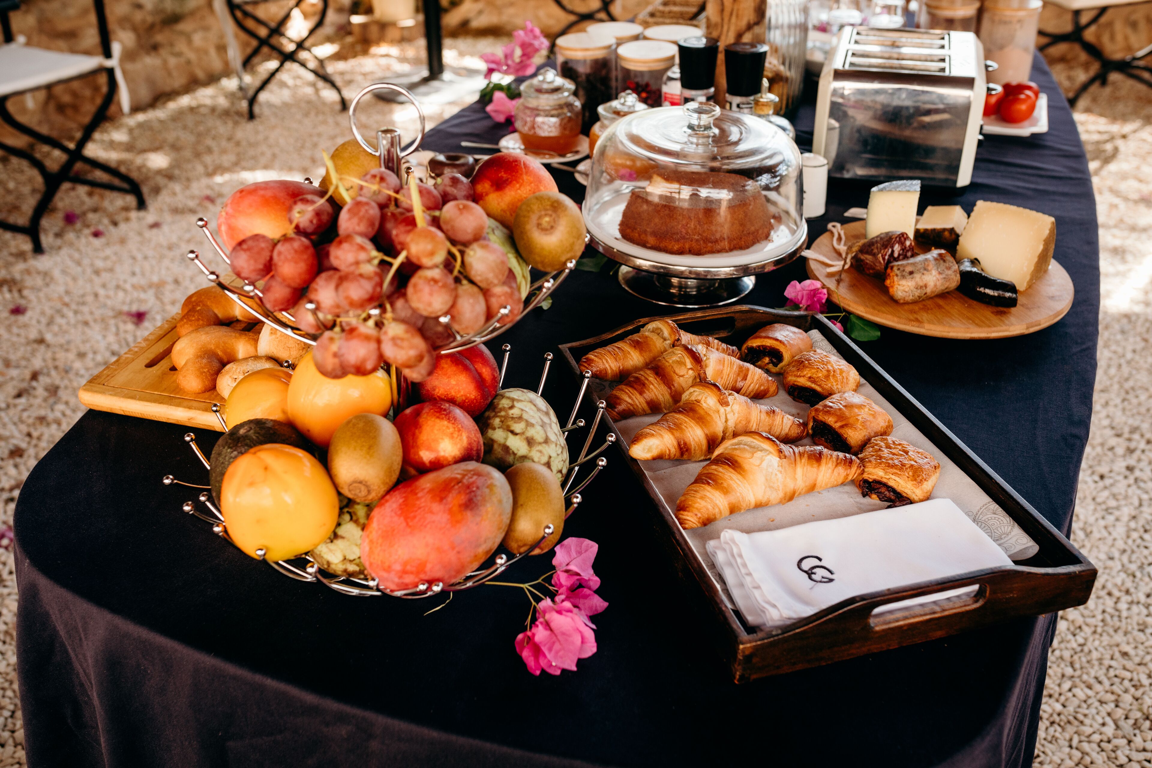 Una mesa con una variedad de frutas, pasteles y quesos, ideal para el desayuno o un tentempié.