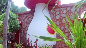 Una estructura grande con forma de hongo y superficie texturizada, rodeada de follaje.