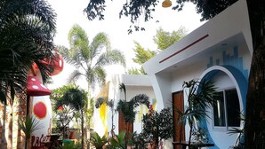 Un patio con una estructura en forma de hongo, un arco azul y varias plantas en macetas.