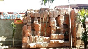 Una pared de piedra con un rostro esculpido, palmeras y un letrero con caracteres chinos.