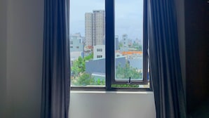A room with a large window, curtains, and a view of a cityscape. - Robin Hotel Danang (Da Nang)