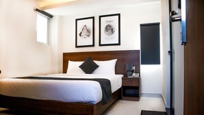 A hotel room with a wooden bed, a nightstand, a framed picture of the moon, and a window. - Robin Hotel Danang (Da Nang)