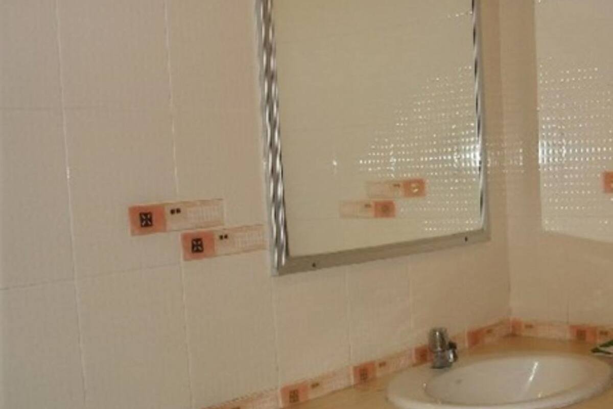 A bathroom with a white sink, a mirror, and a tiled wall with a decorative border.