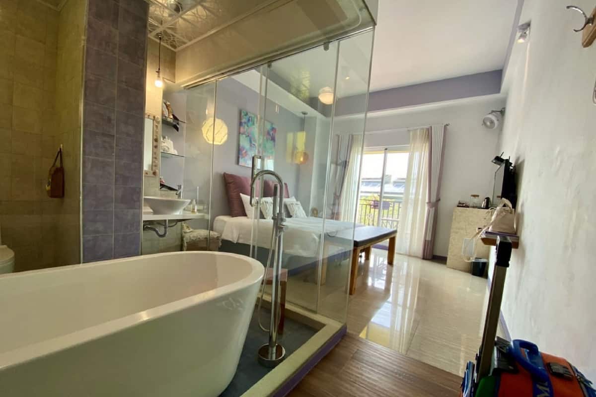 Un baño moderno con una bañera grande, cabina de ducha con mampara de vidrio y balcón visible.
