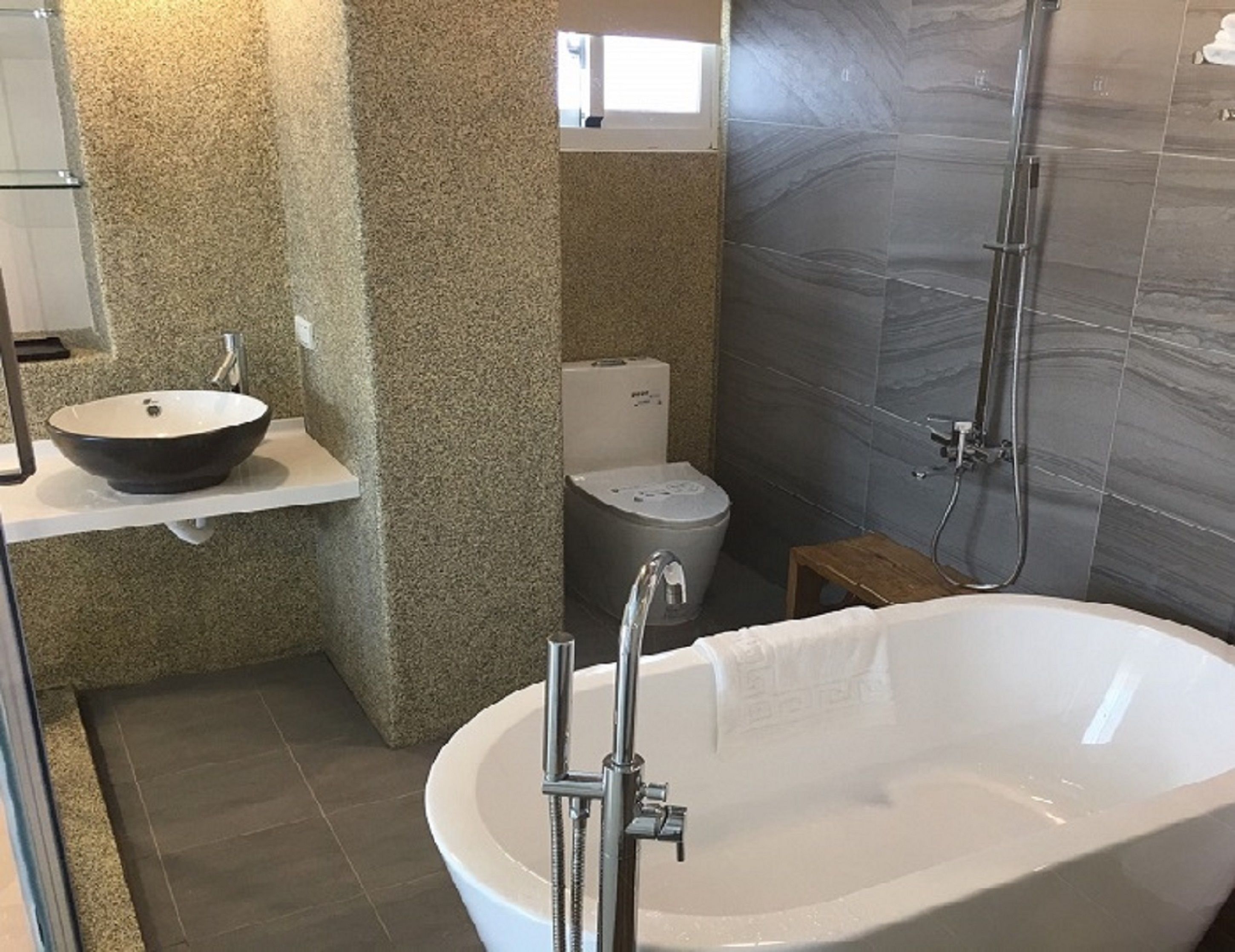 A bathroom with a freestanding bathtub, a sink with a bowl basin, a toilet, and a shower area.