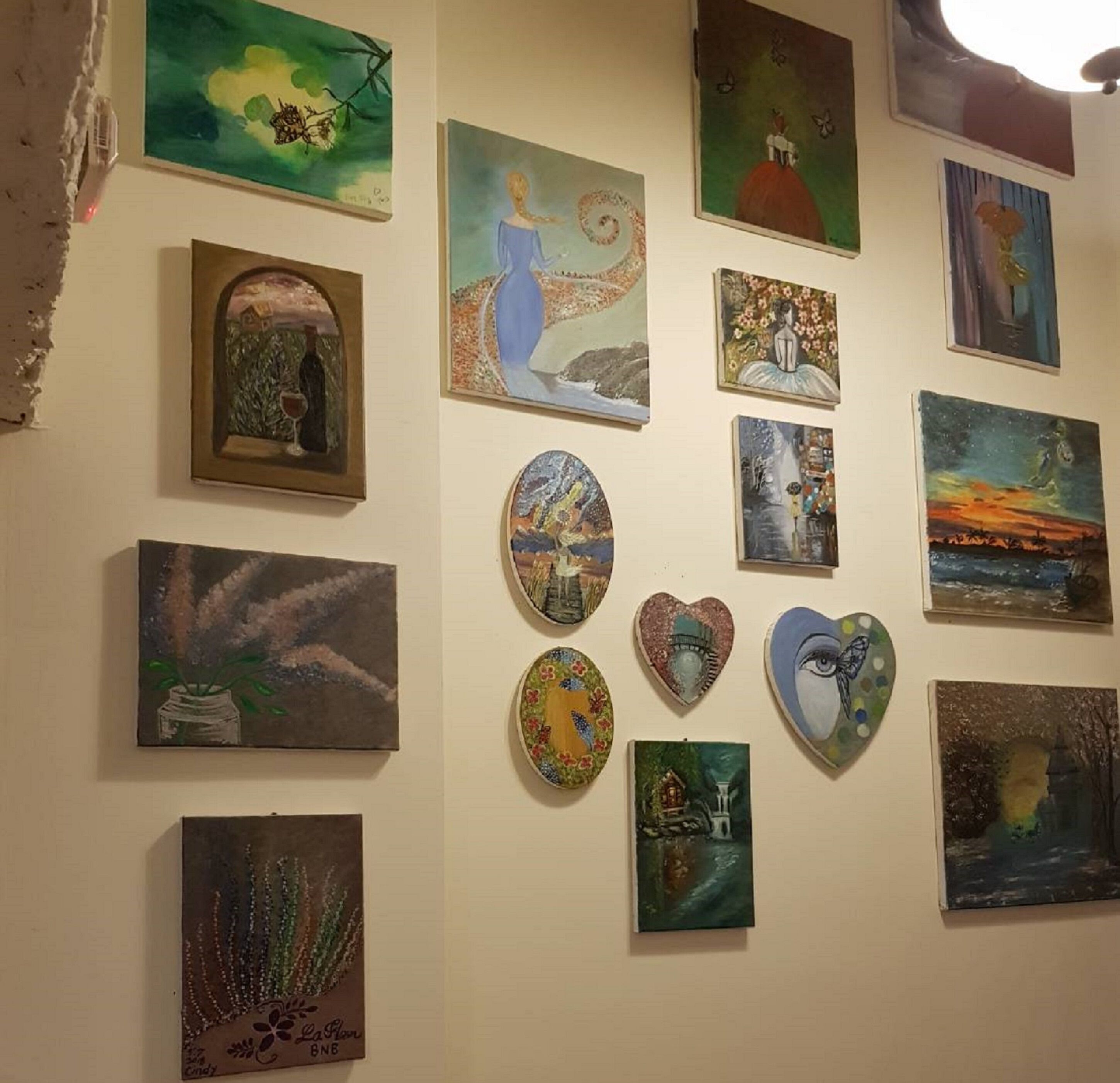 A wall with various artworks including paintings and decorative plates.