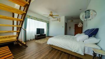 A bedroom with a wooden staircase, a bed with white bedding, a ceiling fan, and a TV on a stand.