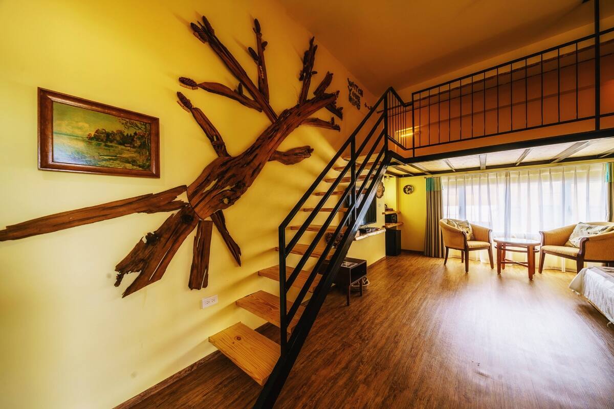 Una habitación con una escalera de madera, un cuadro y un conjunto de sofás.