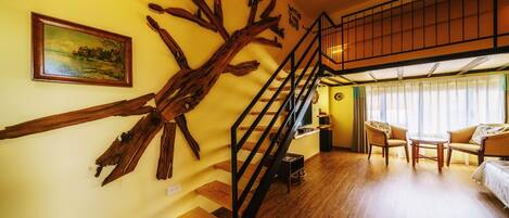 A room with a wooden staircase, a painting, and a sofa set.