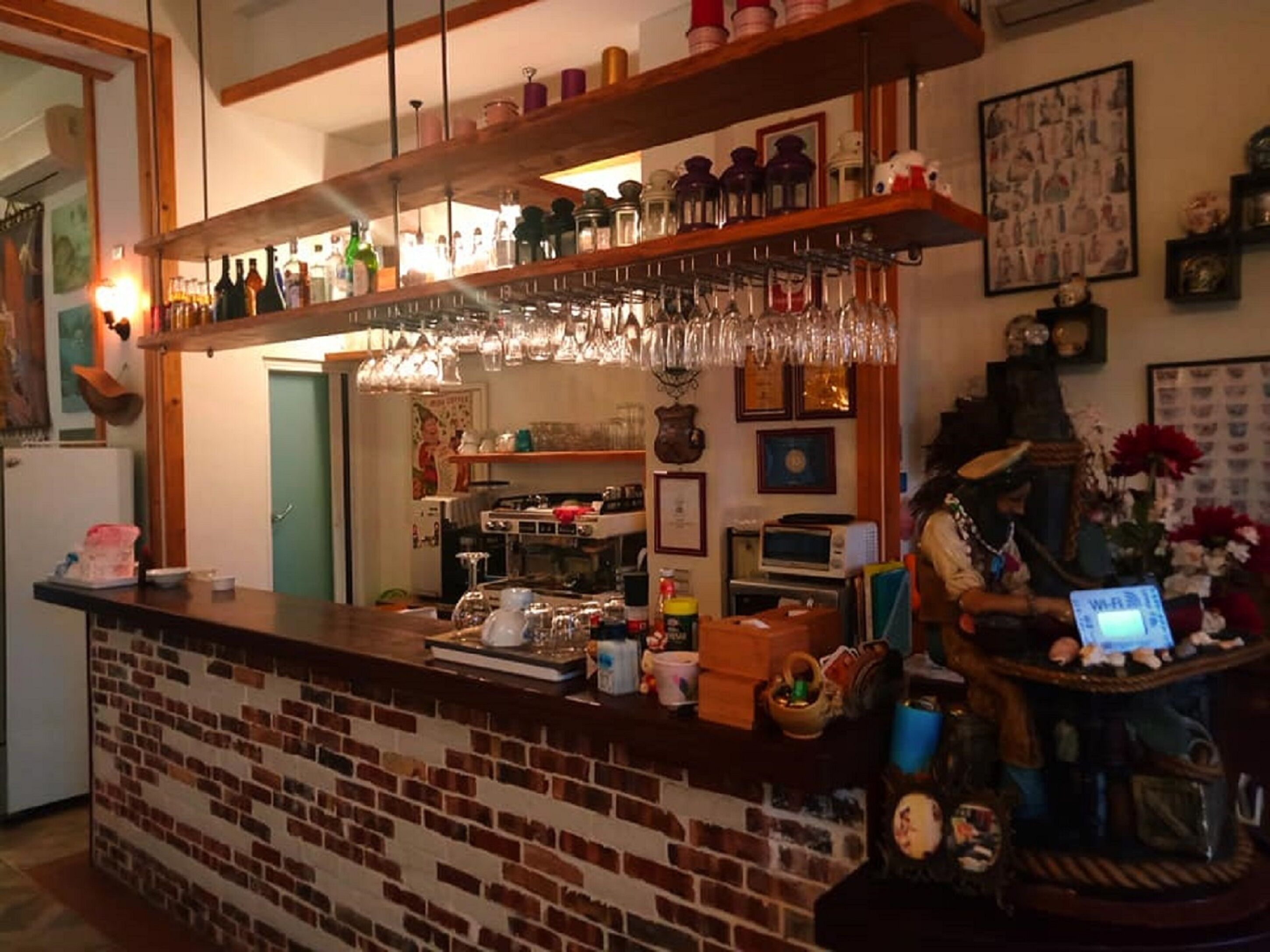 Une cuisine dotée d’un comptoir en briques, d’un porte-bouteilles suspendu et de divers appareils de cuisine.