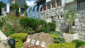A garden with a large rock, a building with blue pipes, and a sign with Chinese characters. - La Fleur B&B (Hengchun)