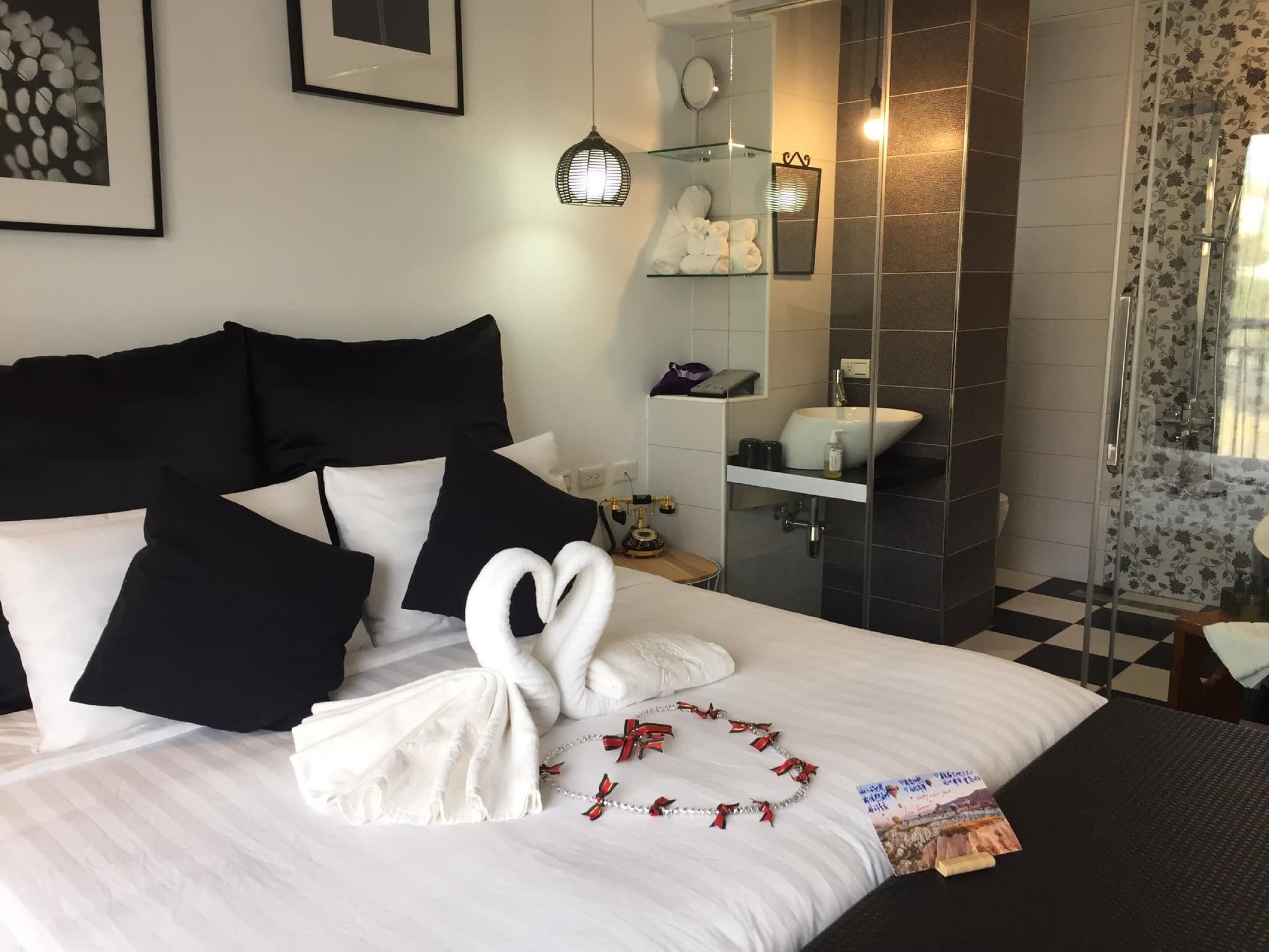 A hotel room with a neatly made bed, a bathroom with a glass shower enclosure, and a checkered floor.