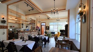 A restaurant with wooden beams, chandeliers, and a brick wall. Tables and chairs are arranged for dining. - La Fleur B&B (Hengchun)