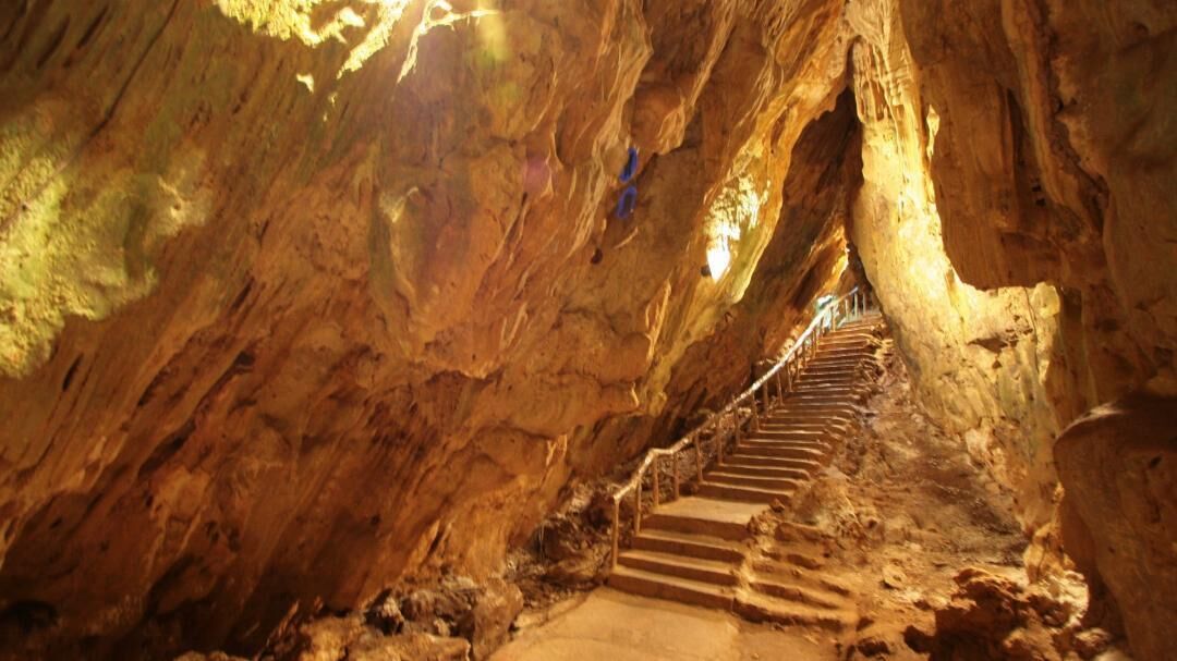Une grotte avec un escalier qui descend vers les profondeurs de la caverne.