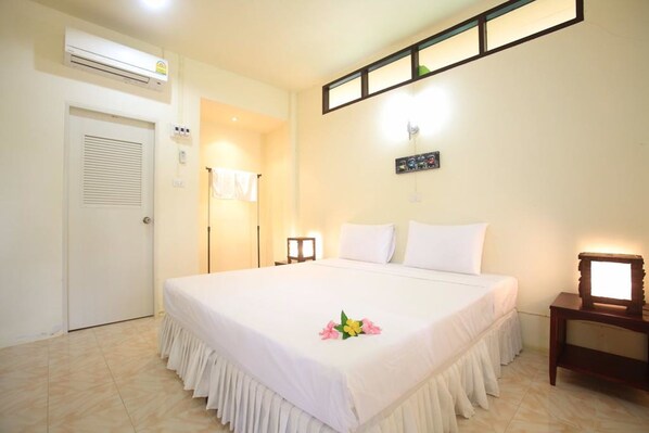 A hotel room with a bed, bedside table, and an air conditioning unit. - Koh Mook Rubertree Bungalow (Ko Mook)
