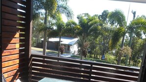 Ein Balkon mit blauem Tisch und schwarzen Stühlen, der auf ein Wohngebiet mit Palmen und Häusern blickt.