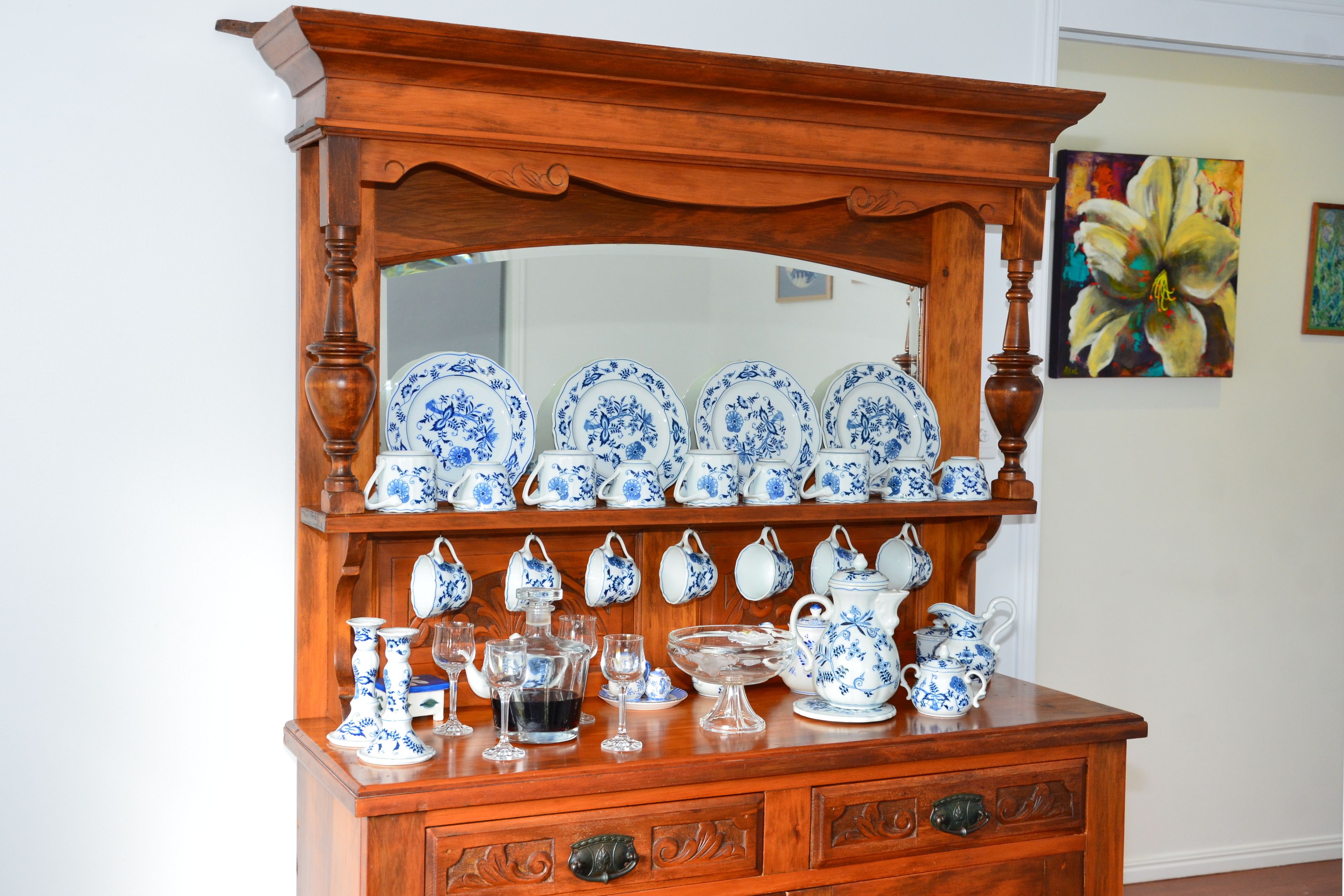 A wooden dresser with a mirror above it, displaying various blue and white ceramic items.