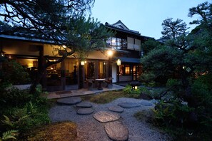 A traditional Japanese-style house with a garden, stone pathway, and outdoor seating area. - Ryokan Kurashiki (Kurashiki)