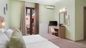 Quarto de hotel com cama, escrivaninha, cadeira, televisão e ar condicionado.