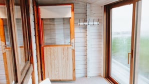 Ein Interieur einer Holzhütte mit Holzbalkendecke, einem weißen Tisch und einem großen Fenster.