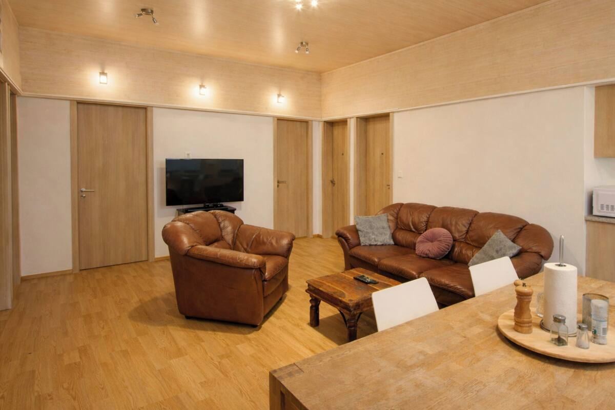 A modern living room with two leather sofas, a wooden coffee table, and a television mounted on the wall.