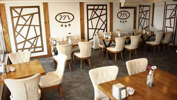 Un restaurante con varias mesas y sillas, detalles de madera y paneles decorativos en las paredes.