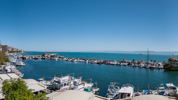 A marina with various boats docked, a clear blue sky, and distant mountains. - Sinop Mola Otel (Sinop)