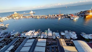 A marina with numerous boats docked, a large ship in the background, and a covered area with tables and chairs. - Sinop Mola Otel (Sinop)